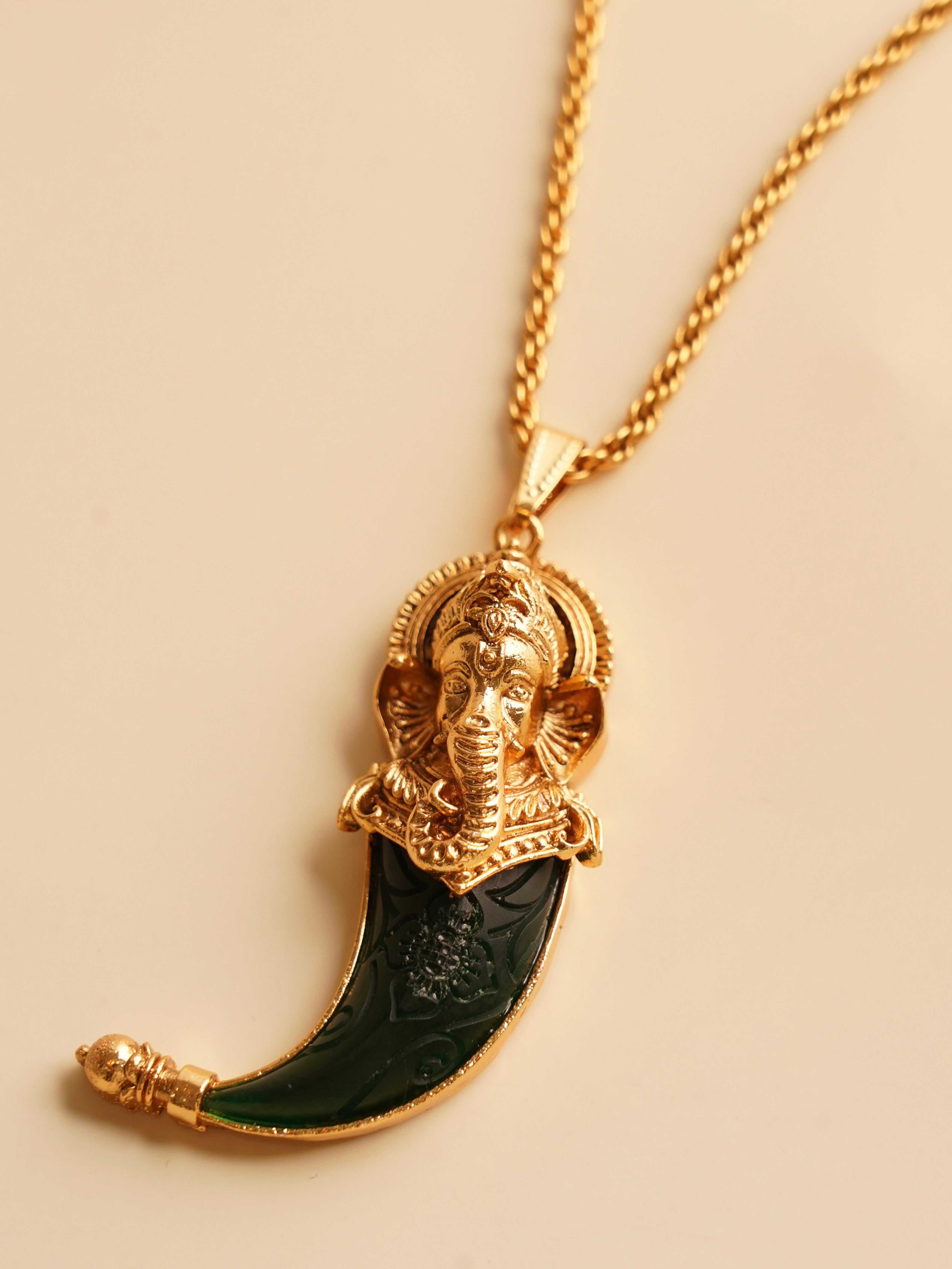 Close-up of pendant featuring ganesha motif and gold finish on copper alloy